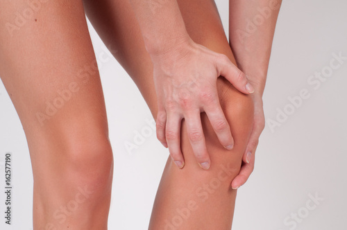  Woman massaging her painful knee, feeling pain in knee.