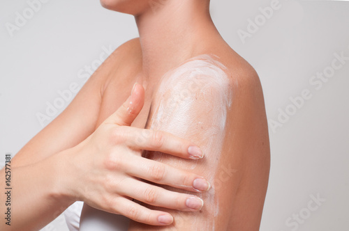 Body care. Woman cares about her shoulder applying cosmetic cream