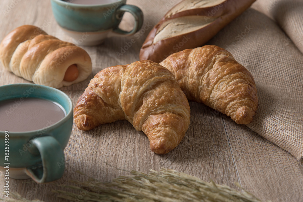 Croissants with bread and coffee cup on wooden background Croissants with bread and coffee cup on wooden background