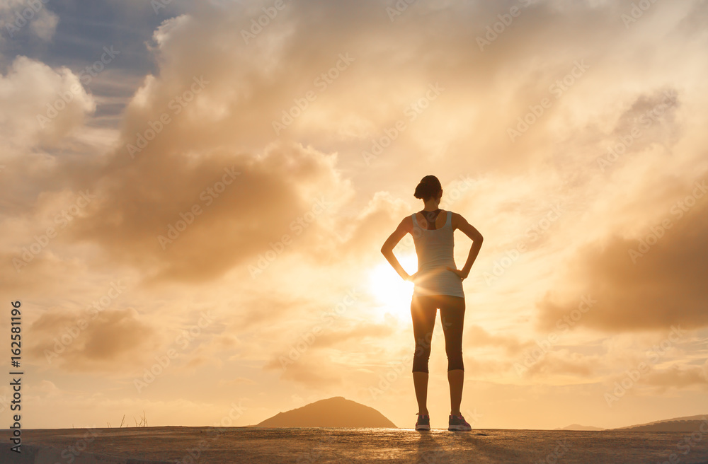 Fit female standing watching the sunrise. Active lifestyle concept. 
