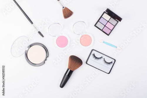 Top view of A collection of cosmetic beauty products arranged around a blank space on a white background.