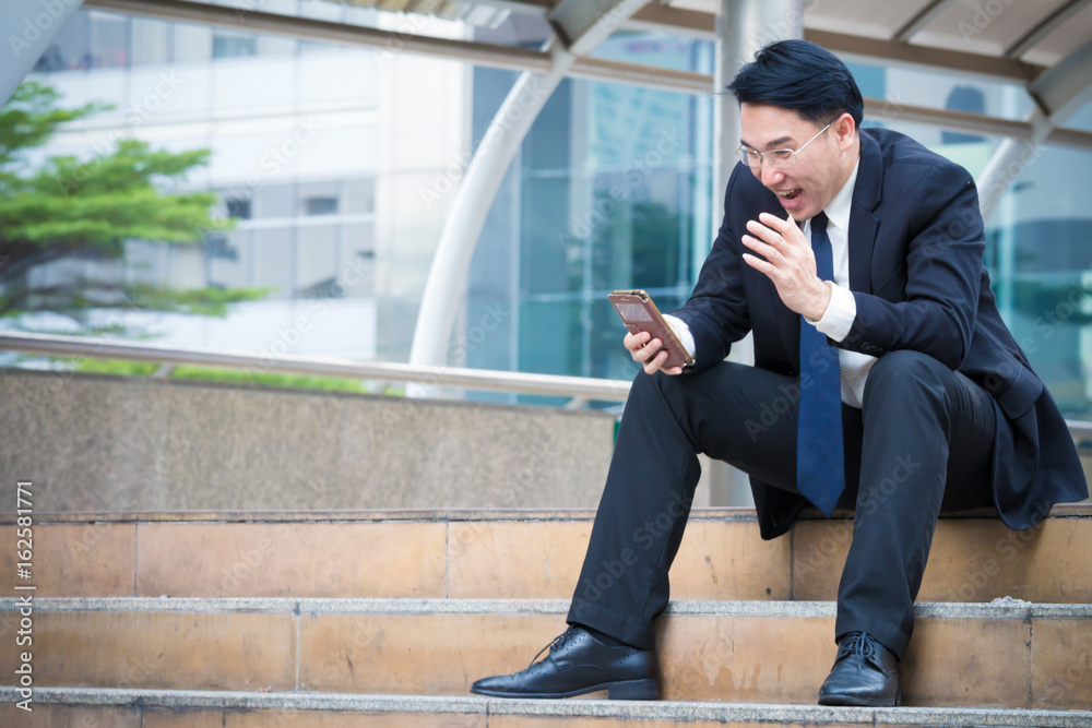 Businessman looking at his smart phone and his face is so happy when stock index is going up and have good news for his project Businessman looking at his smart phone and his face is so happy when stock index is going up and have good news for his project
