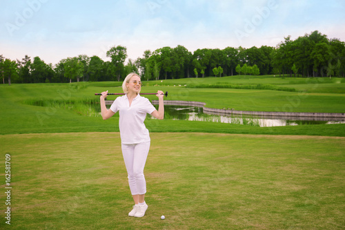 Beautiful young woman on golf course in summer day