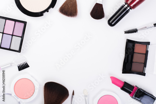 Top view of A collection of cosmetic beauty products arranged around a blank space on a white background.