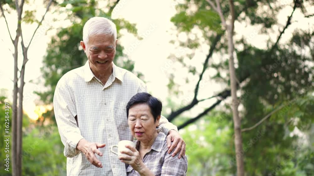 Asian senior couple showing affectionate and care through a cup of coffee in morning bright natural park Asian senior couple showing affectionate and care through a cup of coffee in morning bright natural park