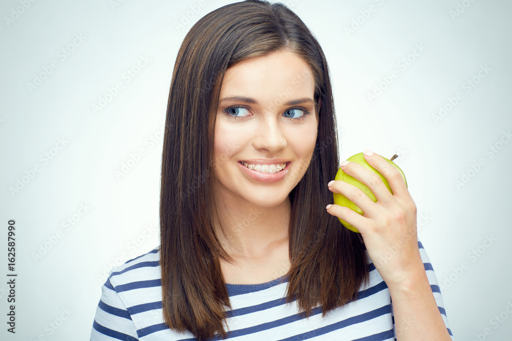 Close up smiling face portrait of young woman with braces on teeth holding green apple. Close up smiling face portrait of young woman with braces on teeth holding green apple.