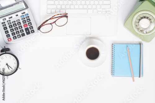 Flat lay of workspace desk with white laptop, stationery and cup of coffee