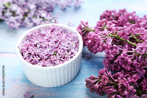 Lilac flowers in bowl on blue wooden table