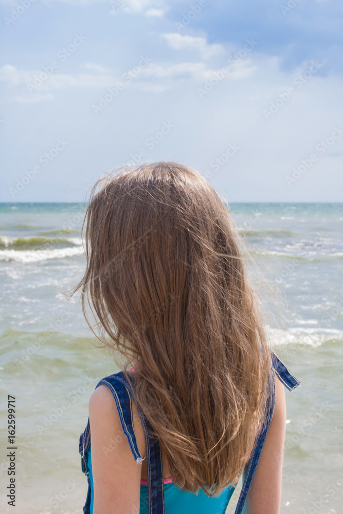 Young girl with long blond hair on the sea coast Young girl with long blond hair on the sea coast