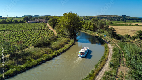 Aerial top view of boat in Canal du Midi from above, family travel by barge and vacation in Southern France 