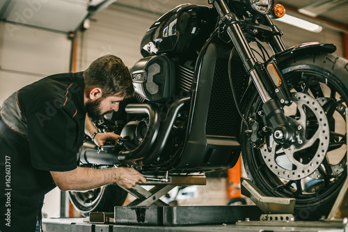 Professional mechanic change the oil in a motorcycle. The sports bike is on the lift.