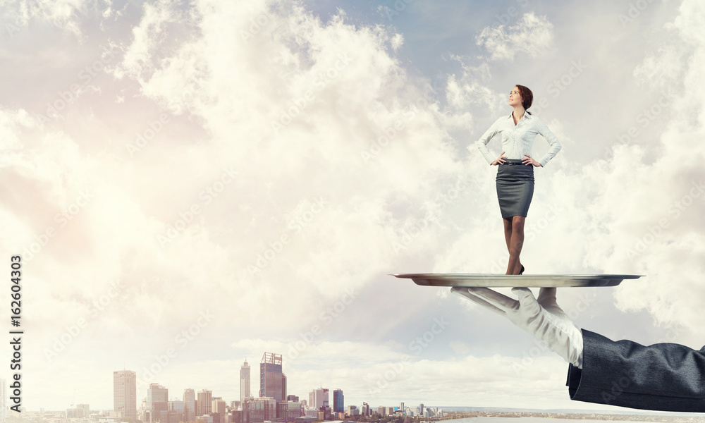Confident elegant businesswoman presented on metal tray against cityscape background Confident elegant businesswoman presented on metal tray against cityscape background