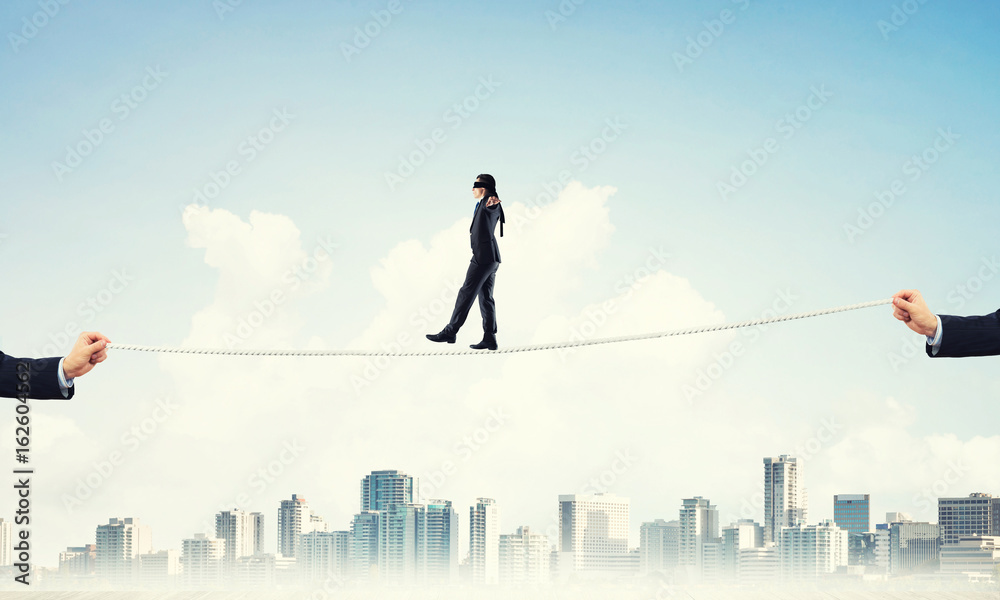 Business concept of risk support and assistance with man balancing on rope Business concept of risk support and assistance with man balancing on rope