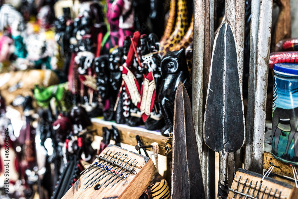 african spears and national wooden figures at local african souvenir market