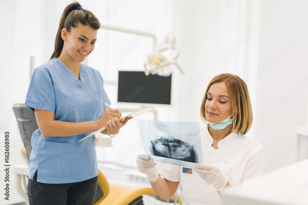 Fototapeta premium woman dentist with her assistant examine dental x-ray