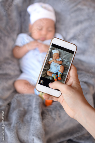 Mom is taking baby photos with a smartphone.
