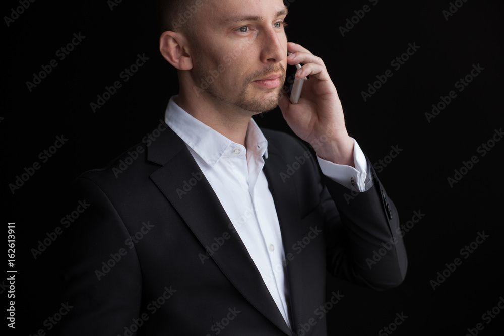 Young bisnessman talking by mobile phone isolated on black background. Young bisnessman talking by mobile phone isolated on black background.