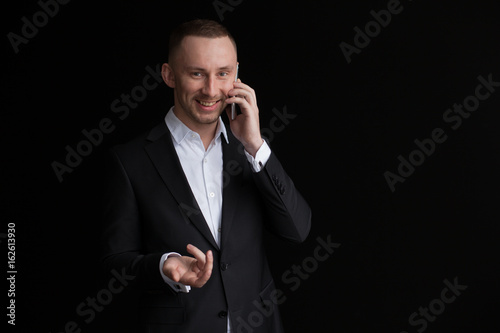 Young bisnessman talking by mobile phone isolated on black background. photo