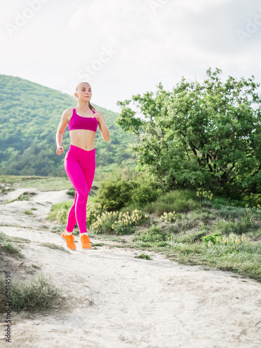 Fitness slim woman running in nature. Sporty girl in mountains.