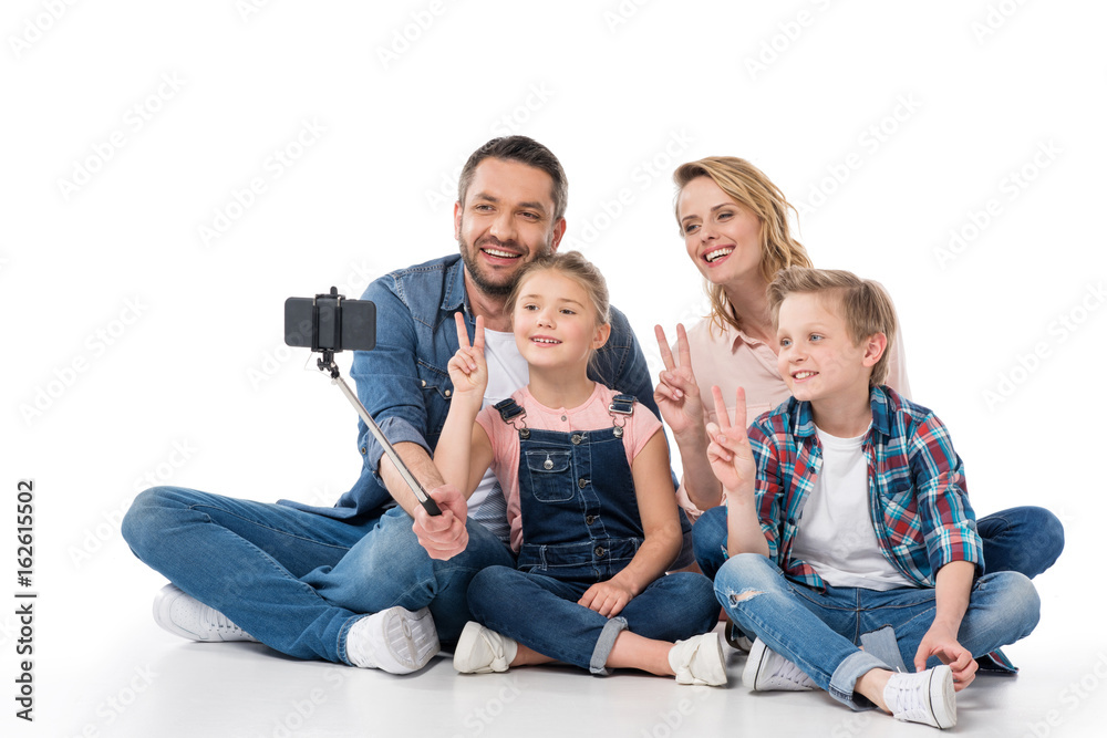 happy family taking selfie on smartphone while showing peace symbols isolated on white