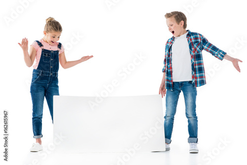 Surprised little children looking at blank placard isolated on white