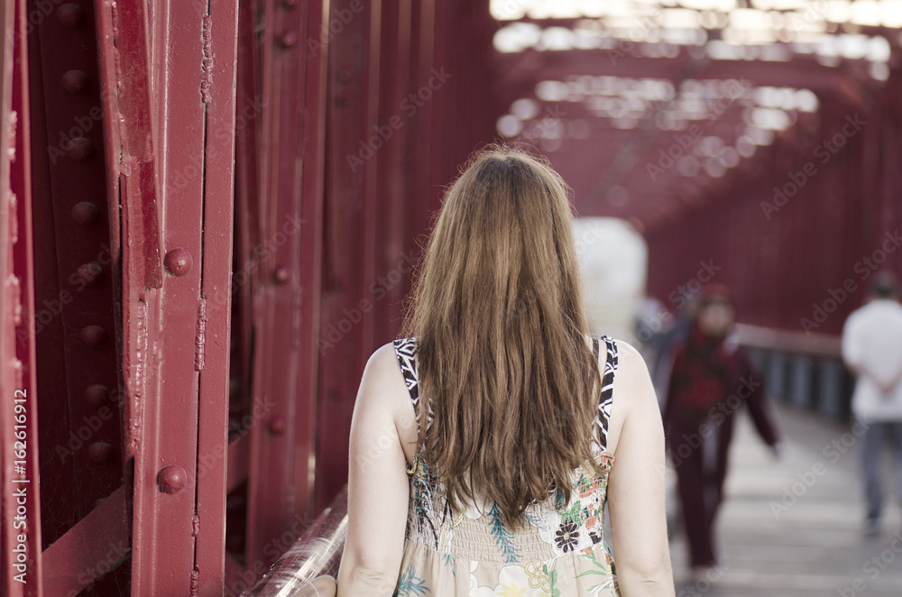 Fototapeta premium Back woman standing on a red bridge over Ebro, Spain