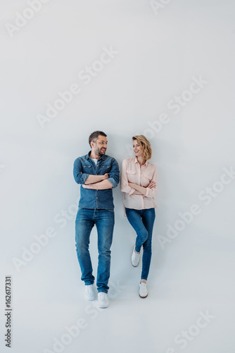young smiling couple standing together with arms crossed