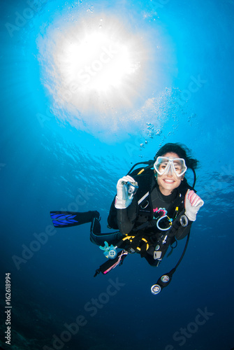 Beautiful Scuba diver smile with underwater Ambient light in the blue sea. photo