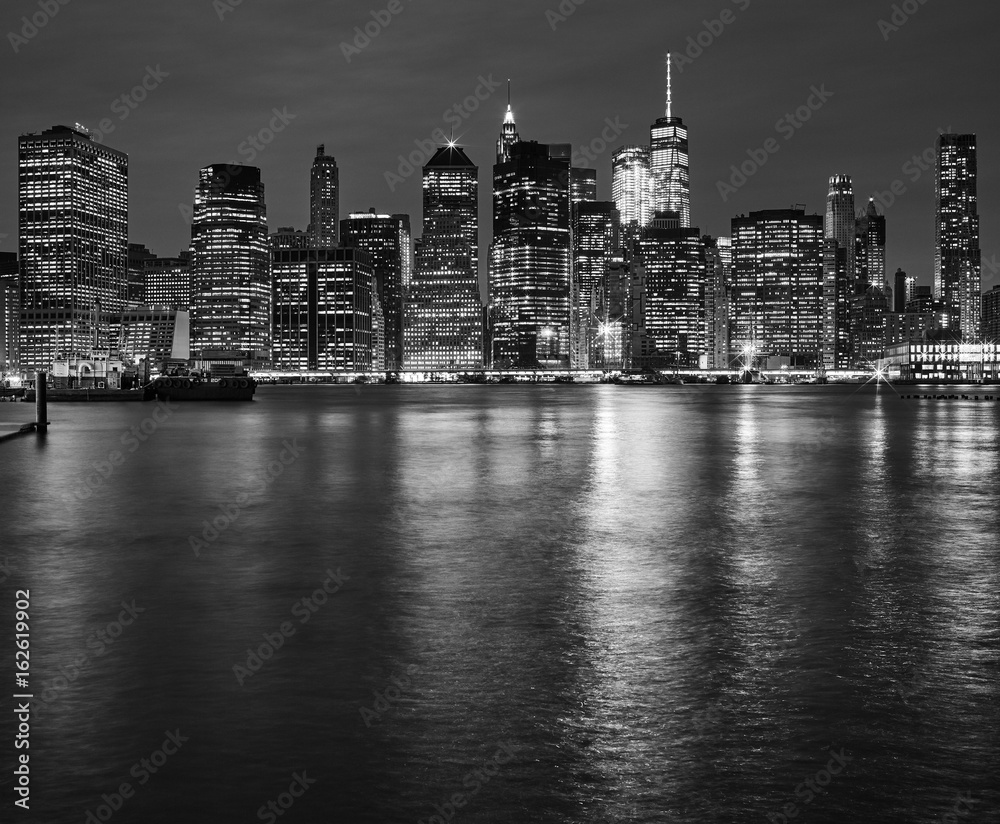 Manhattan skyline reflected in East River at night, New York City, USA.