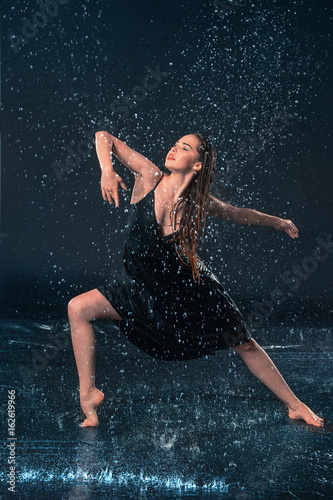 The young beautiful modern dancer dancing under water drops