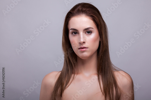Gorgeous model in bra with natural make up on gray background in studio photo. Beauty and fashion.