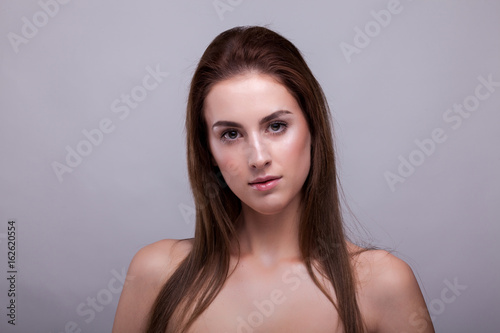 Gorgeous woman with natural make up on gray background in studio photo. Beauty and fashion.