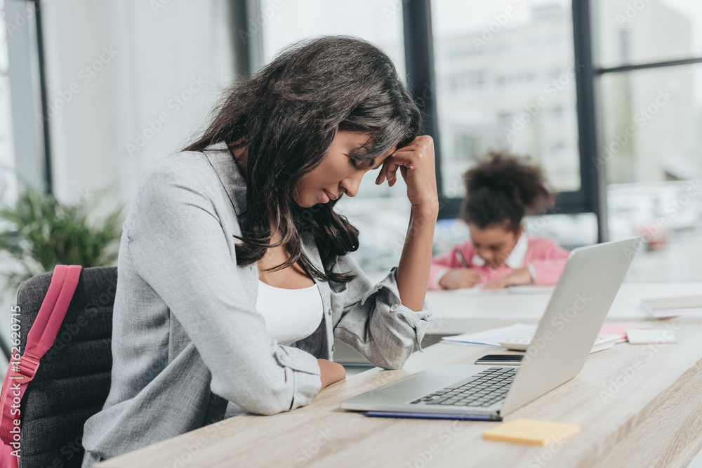 Φωτογραφία side view of exhausted businesswoman sitting at workplace in front of laptop