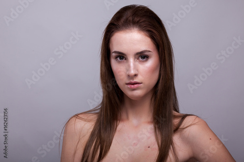 Beautiful woman with perfect skin on gray background in studio photo. Beauty and fashion.
