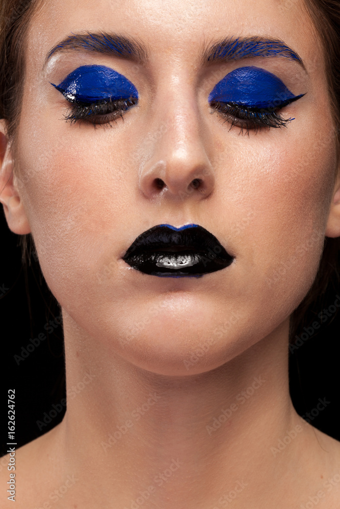 Close up portrait of woman wearing blue make up with black lips in studio photo. Beauty and fashion. Cosmetic and creative artistic make up