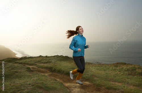 A young Woman jogging along a cliff path photo