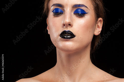 Beautiful woman wearing extravagant blue make up with black lips in studio photo. Beauty and fashion. Cosmetic and creative artistic make up