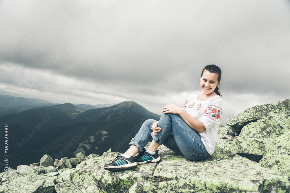 Young pretty woman in national ukrainian dress on the peak of the carpathian mountains