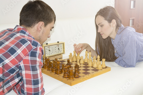 Relaxed young couple playing chess at home lying on sofa. won - Friendship.