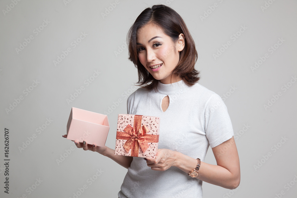 Young Asian woman open a golden gift box. Young Asian woman open a golden gift box.