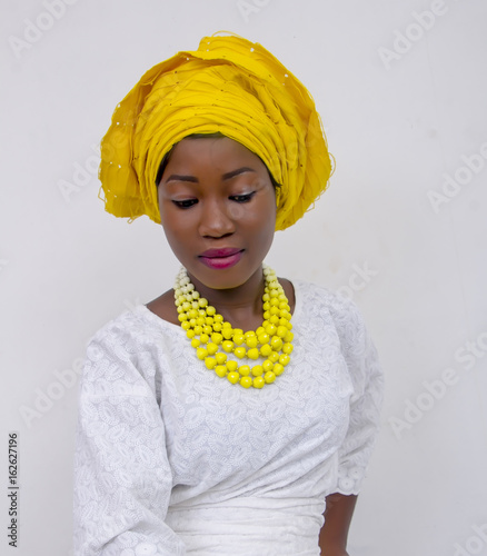 an African lady with head tie, bead necklace, beautiful makeup and smiling photo