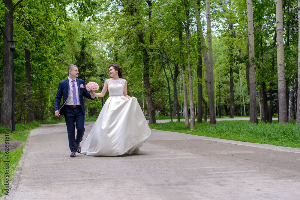 The bride and groom walk in the park The bride and groom walk in the park