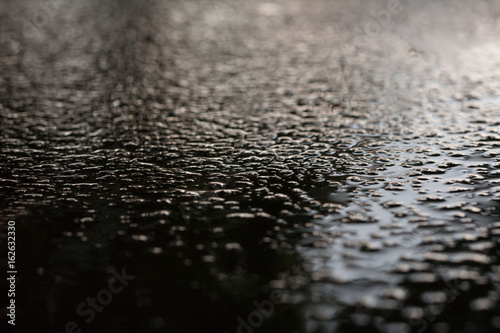 Wet asphalt sidewalk background after heavy rain soft focus.