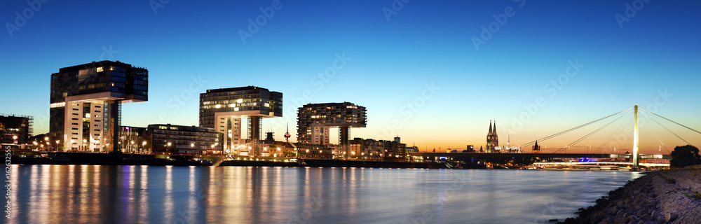 panoramic view to the Cologne harbor, Germany with the river Rhine, cathedral and crane houses during sunset