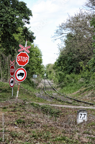 Stop signs with cross by straight railway