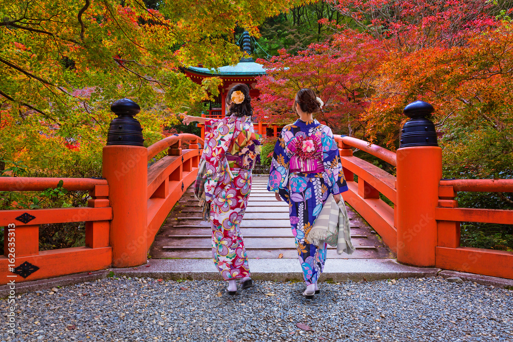 Naklejka premium Kobiety w kimonach chodzących na kolorowych drzewach klonowych jesienią, Kioto. Japonia