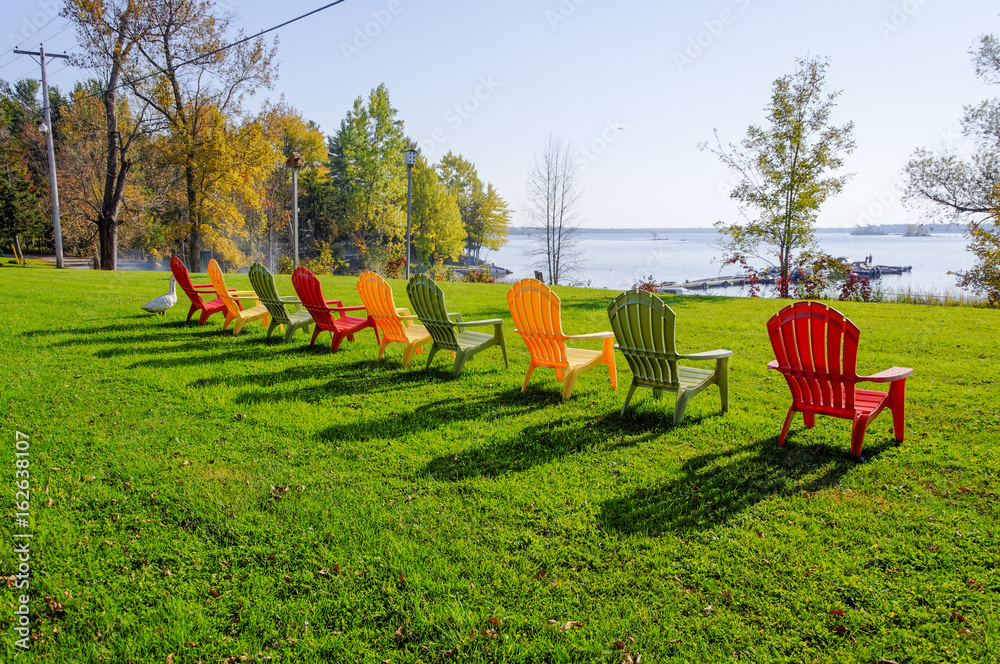 Row of lawn chairs on a green grass background in summer time. Ontario, Canada
