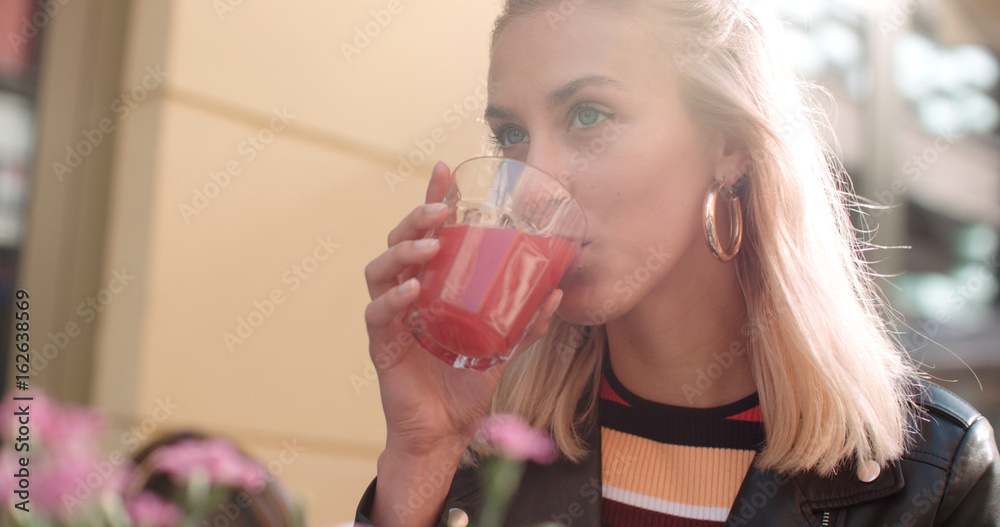 Pretty young caucasian girl sitting at cafe and drinking juice. Pretty young caucasian girl sitting at cafe and drinking juice.
