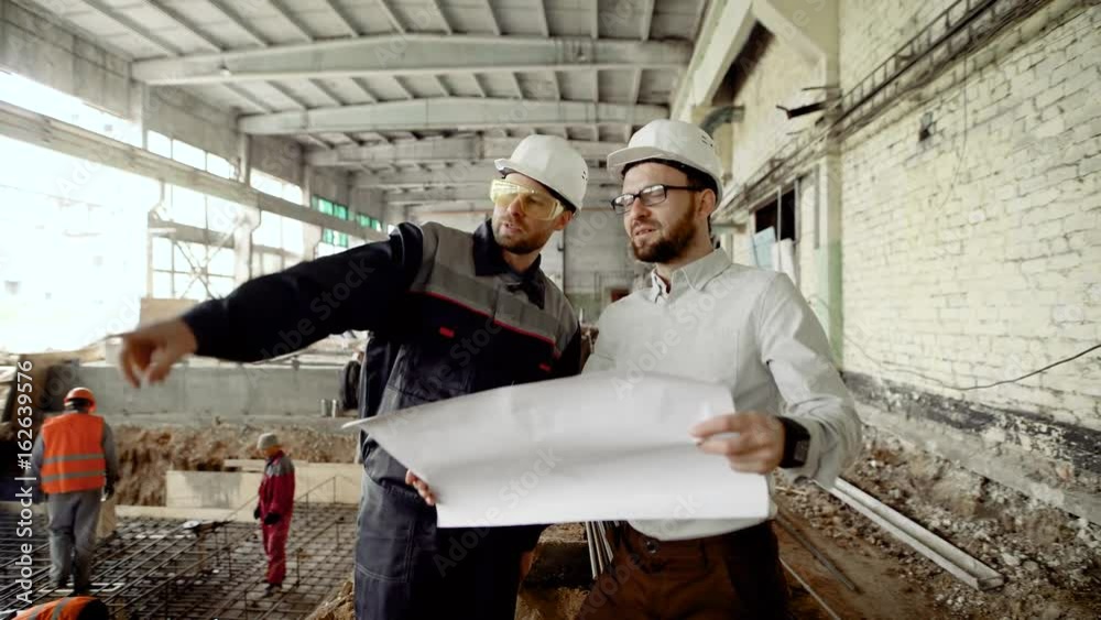 Supervisor and construction worker discussing project. Contractor and builder collaborating on new project plan for renovating old building.