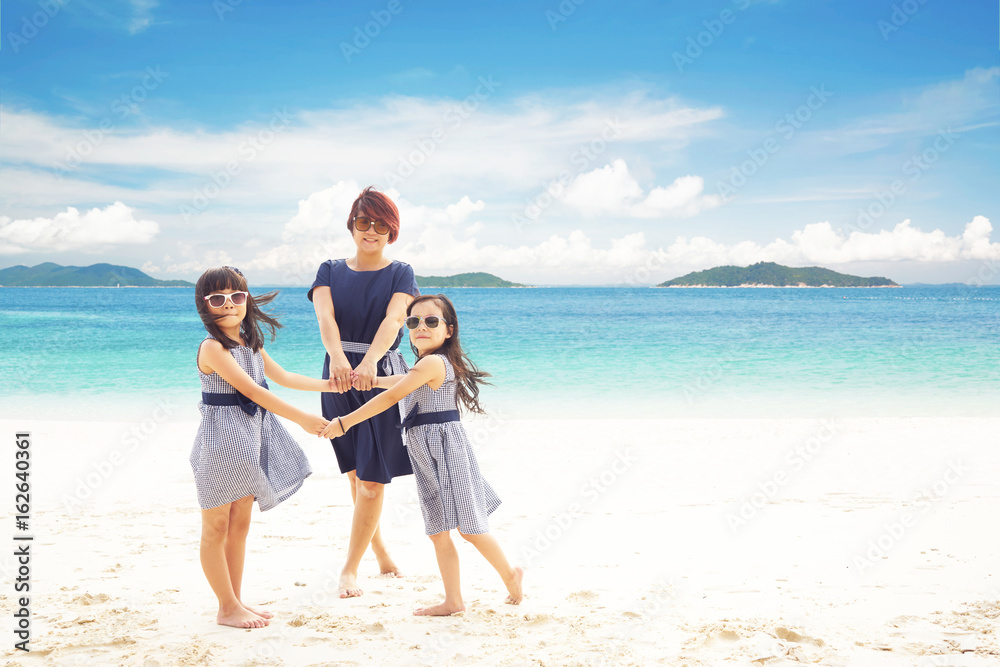Mother with two daughters holding hands on the beach ,enjoying tropical sea vacation .